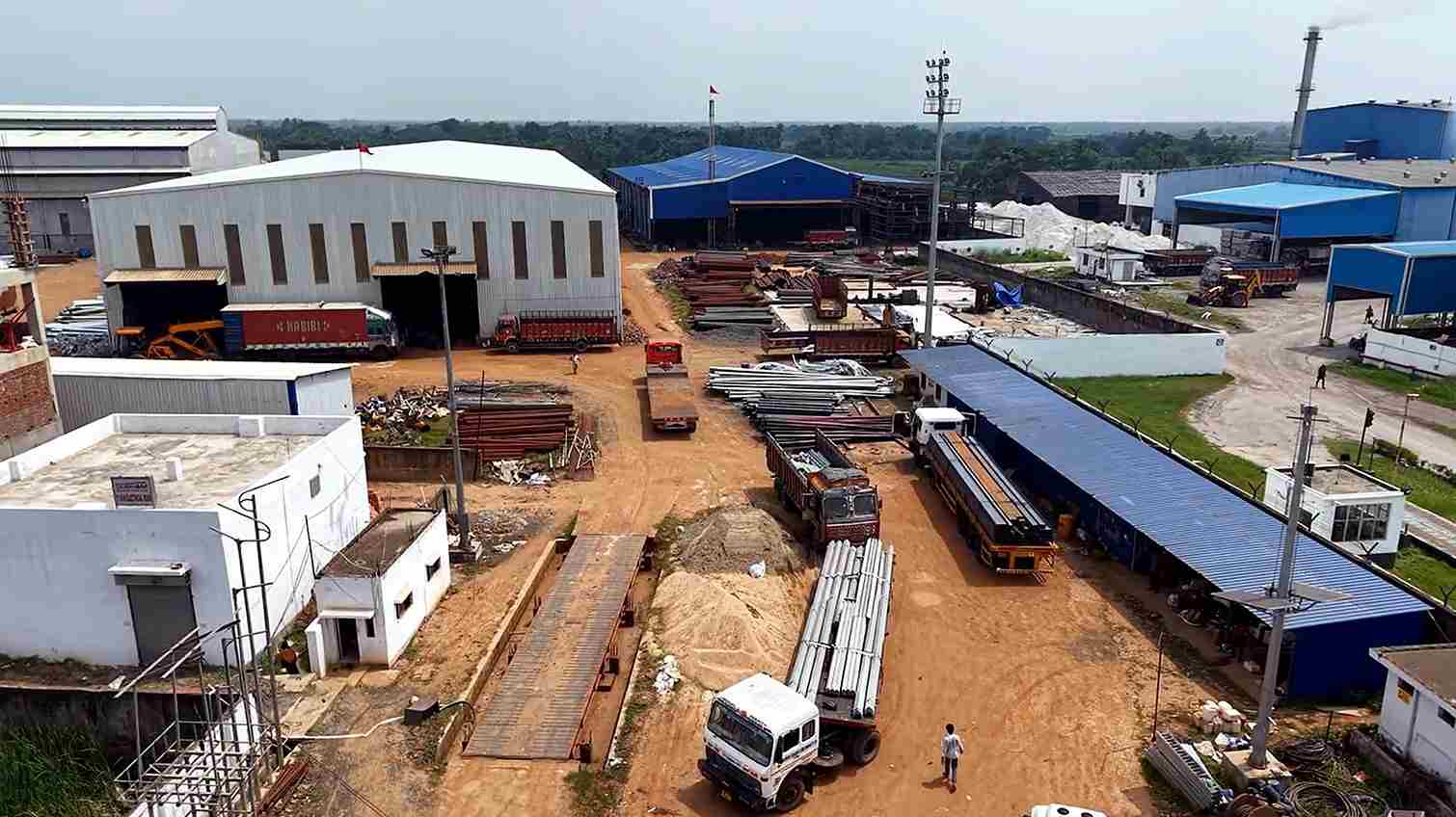 Aerial view of Subham Poles steel pole factory in West Bengal with poles loaded on trucks for dispatch